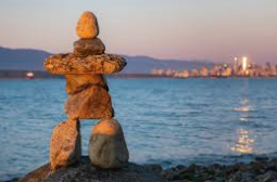 Several inukshuks and a woman becoming one in a beautiful arctic sunset