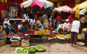 Local people tourists in front of fruit's and vegetable market shop which is on ground. Madagascar.